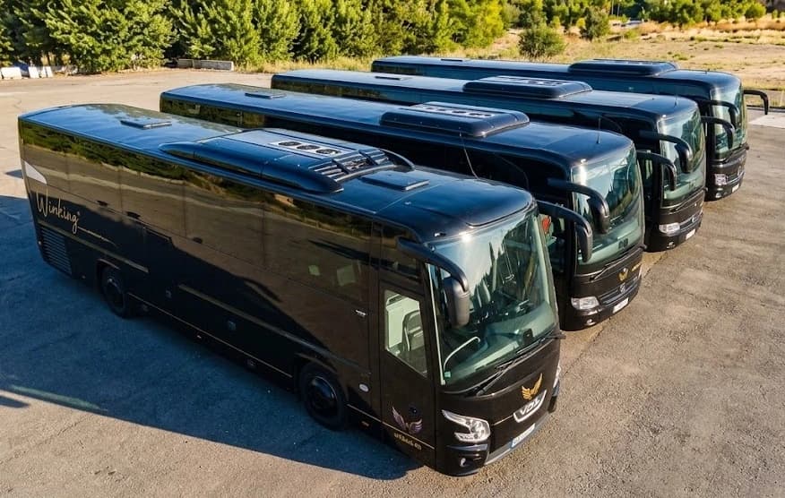 Vista aérea de varios autocares negros de Winking Bus aparcados en una explanada