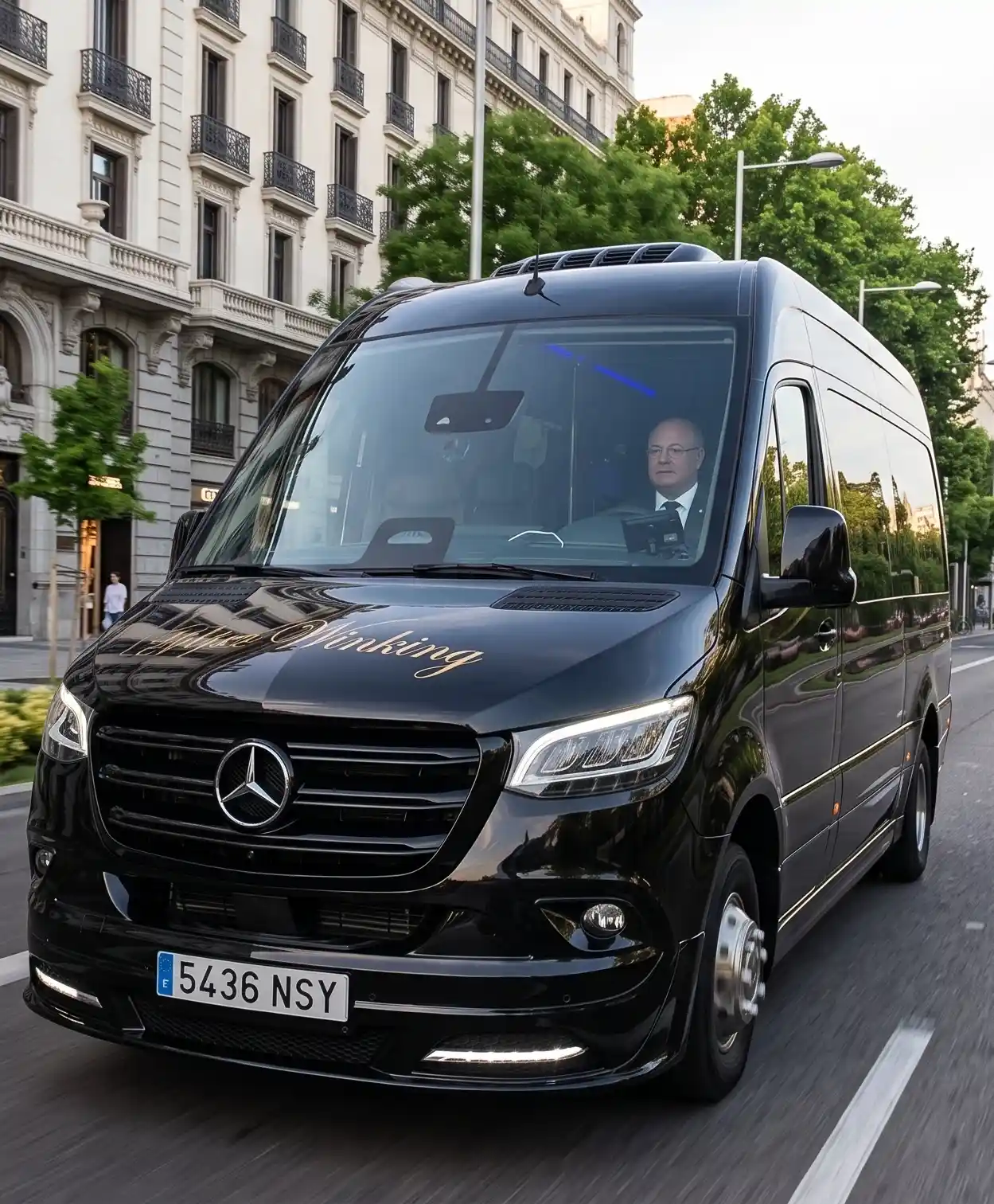 Microbús Mercedes-Benz Sprinter negro de Winking Bus con chófer uniformado al volante y rotulación dorada en el capó, circulando por una avenida céntrica de Madrid